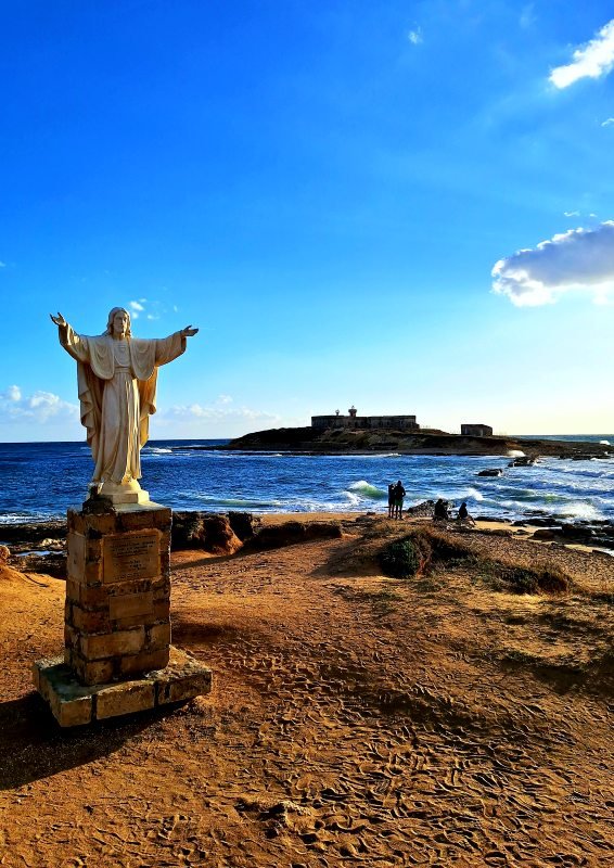 Zachód słońca i pomnik Chrystusa w tle wyspa Isola delle correnti